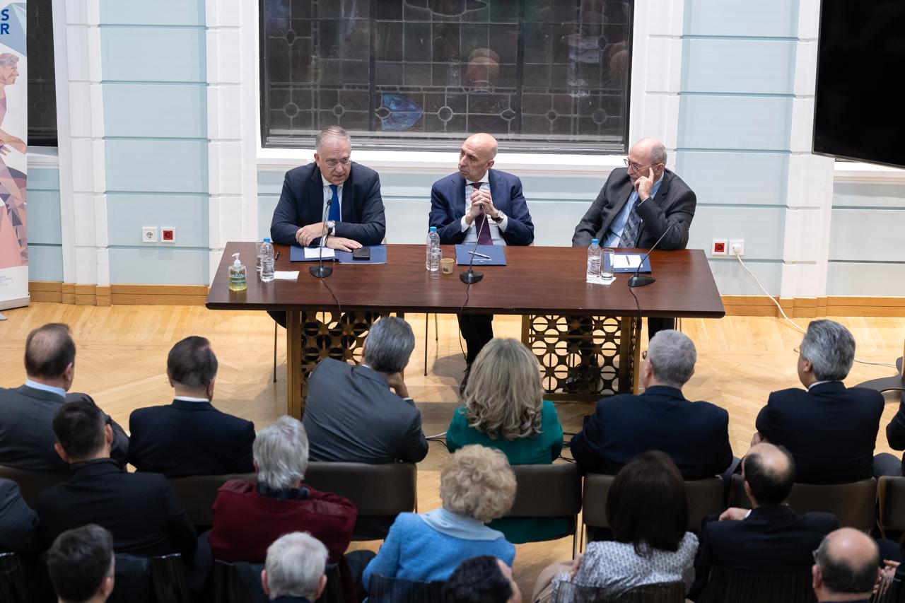 a group of people sitting at a table with a person standing at the podium